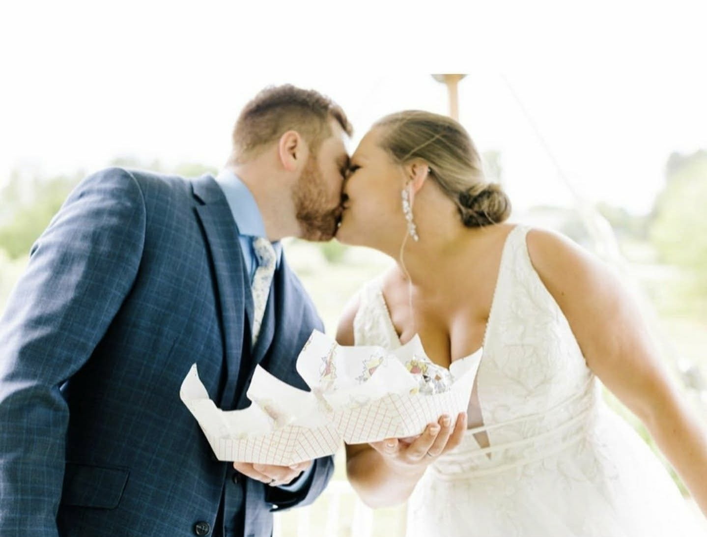 Newlyweds kissing while holding hibachi wraps at their reception