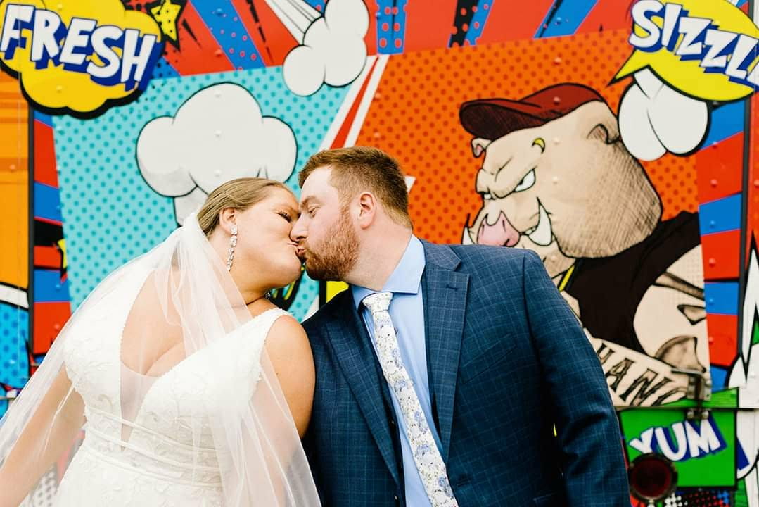Bride and groom sharing a kiss in front of the Nom Nom Ninja food truck