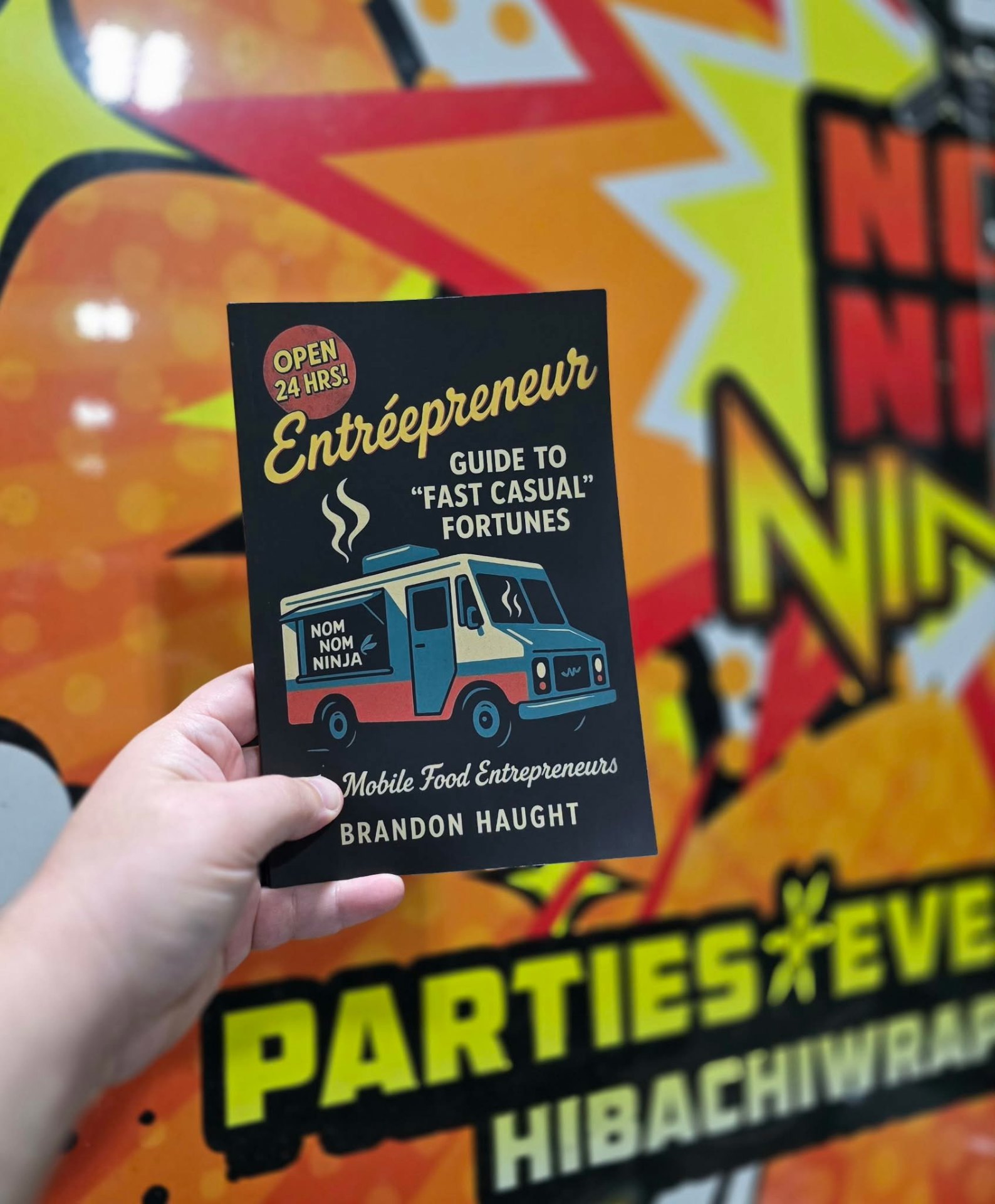 Founder Brandon Haught holding the Entréepreneur book in front of the Nom Nom Ninja truck wrap